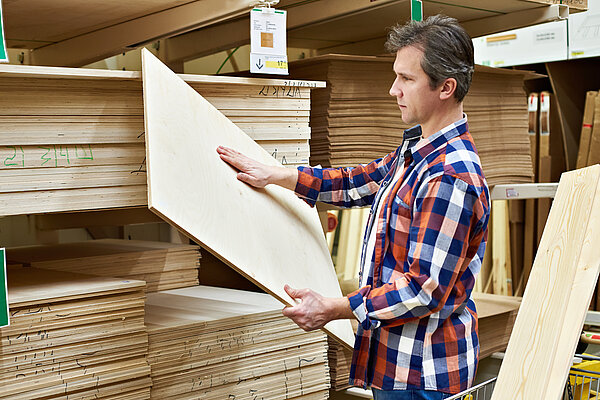Mann sucht Sperrholzplatten im Baumarkt aus