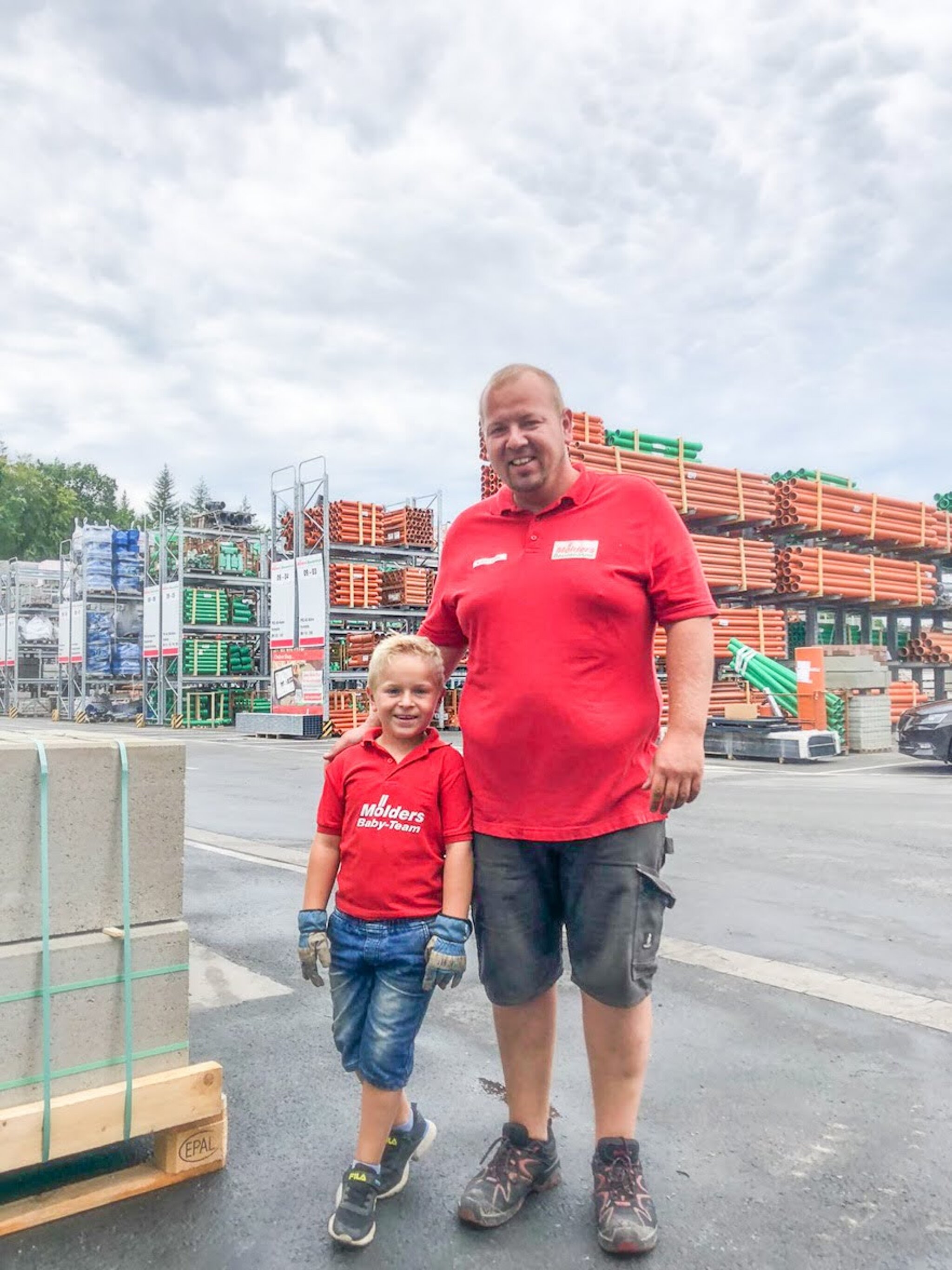 Mölders Lagermitarbeiter steht mit seinem kleinen Sohn auf dem Baustoffhandel Lagerplatz